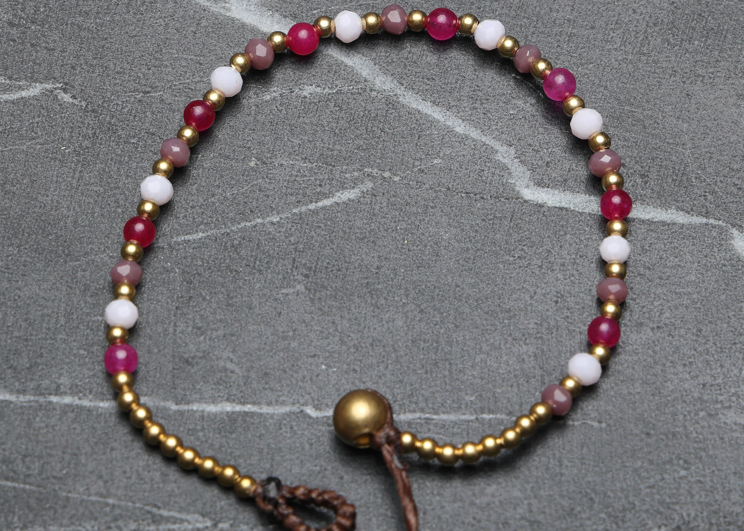 A crystal healing bracelet made of faceted Moonstone crystals on a cotton cord with brass beads.