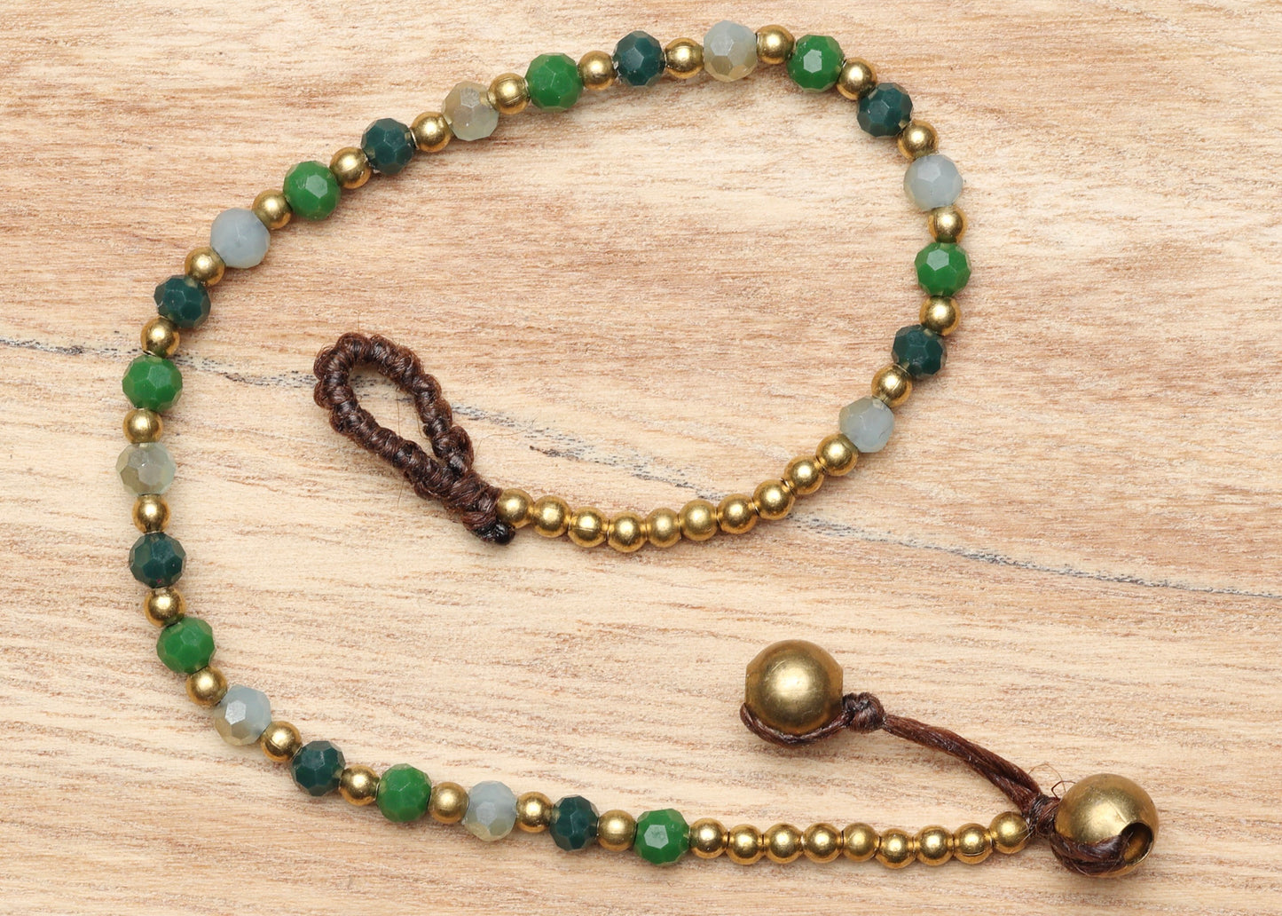 A crystal healing bracelet made of faceted Aventurine crystals on a cotton cord with brass beads