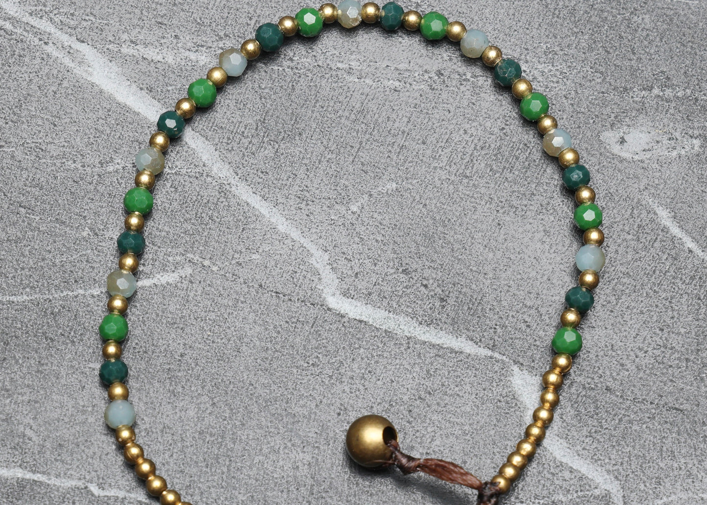 A crystal healing bracelet made of faceted Aventurine crystals on a cotton cord with brass beads