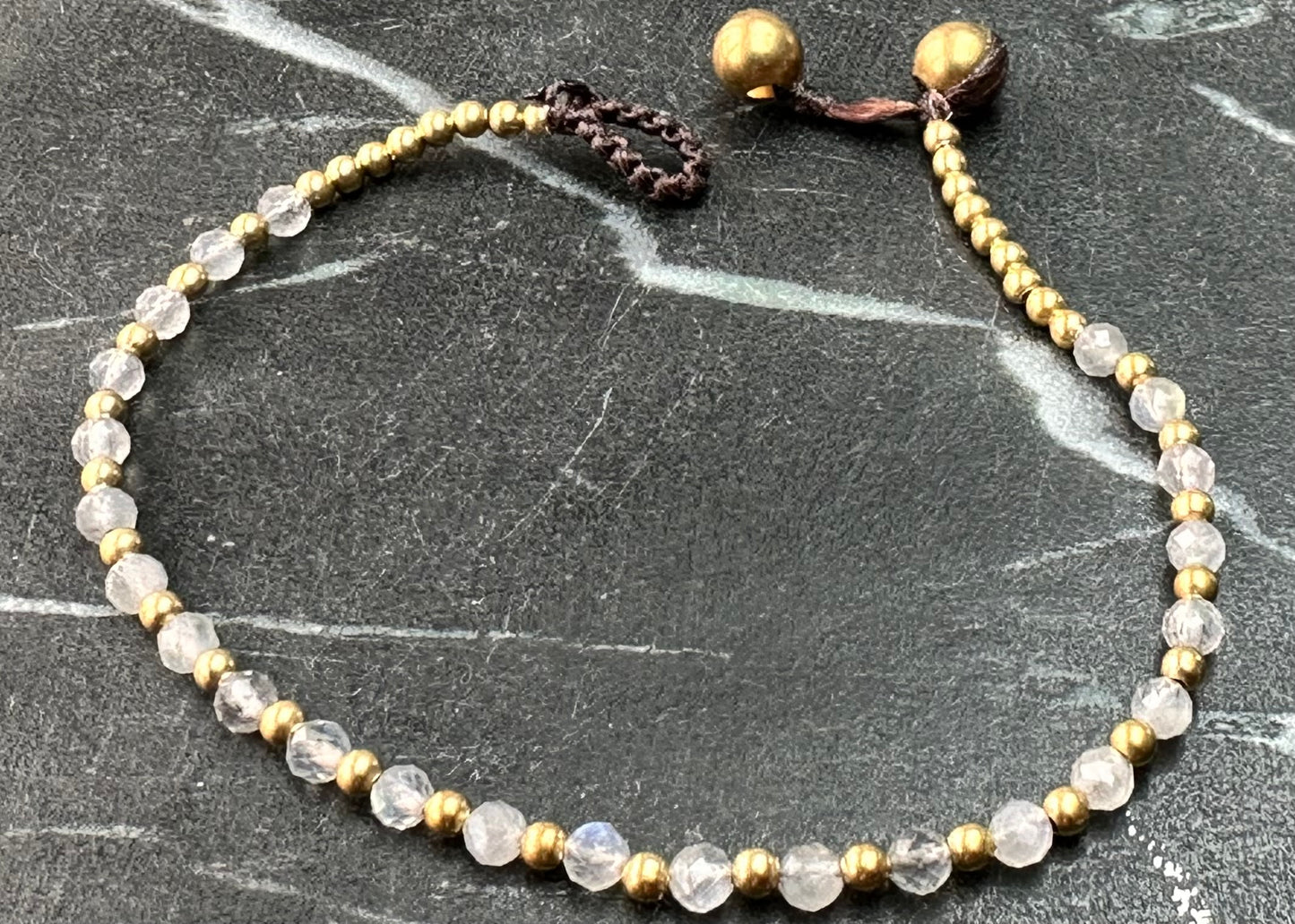 A crystal healing bracelet made of faceted Labradorite crystals on a cotton cord with brass beads