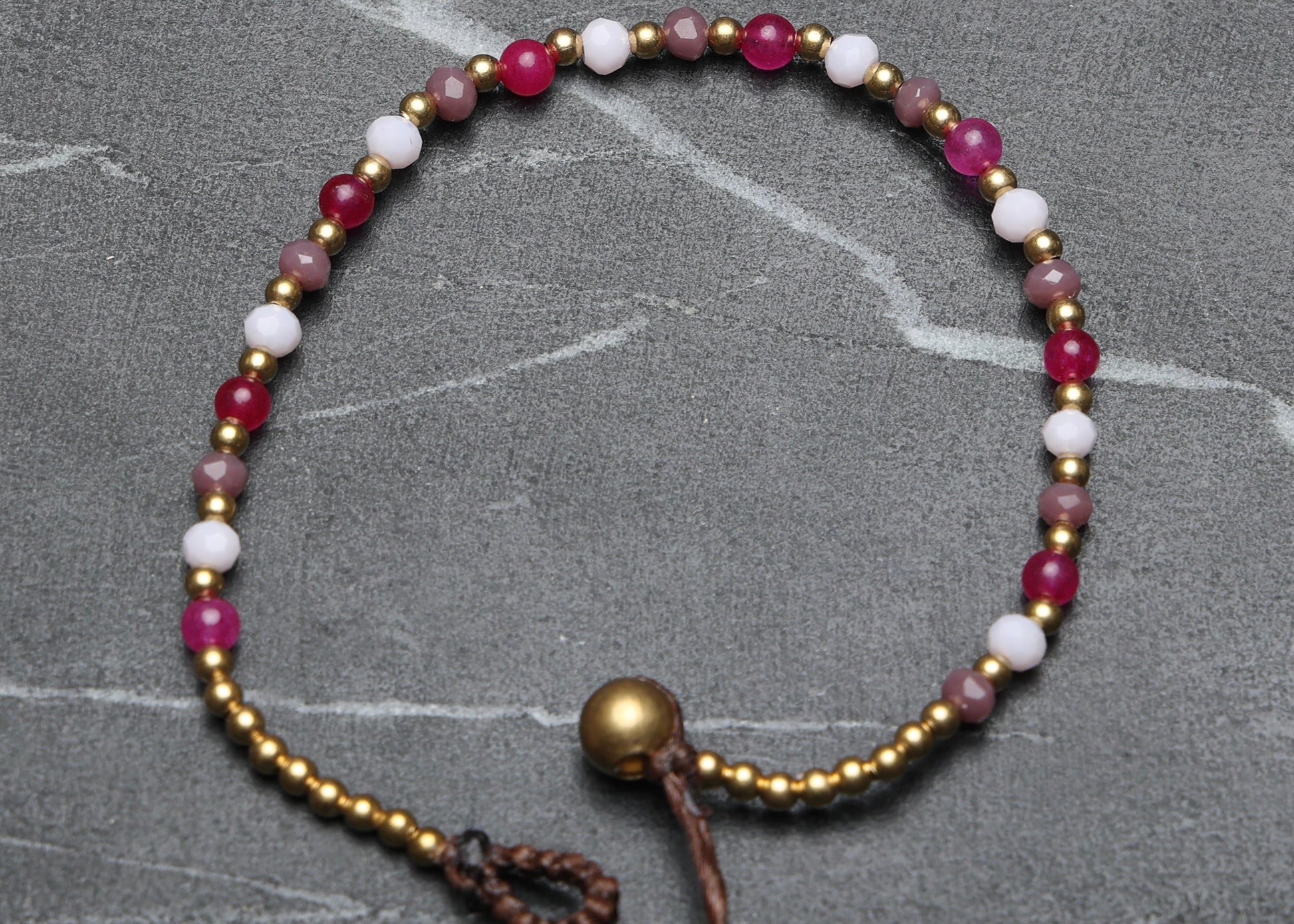A crystal healing bracelet made of faceted Moonstone crystals on a cotton cord with brass beads.