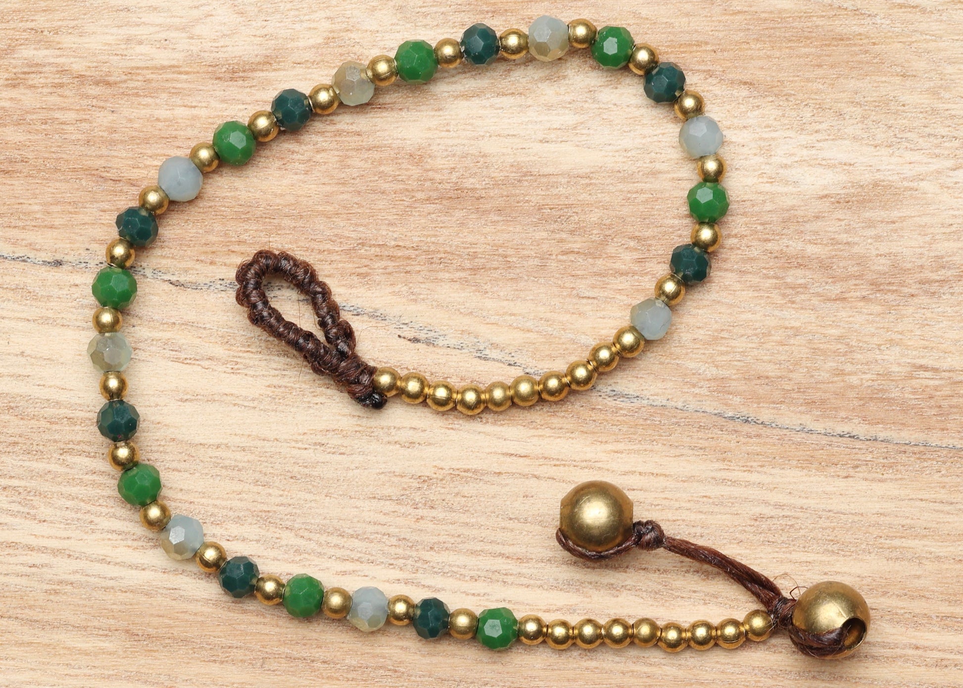 A crystal healing bracelet made of faceted Aventurine crystals on a cotton cord with brass beads