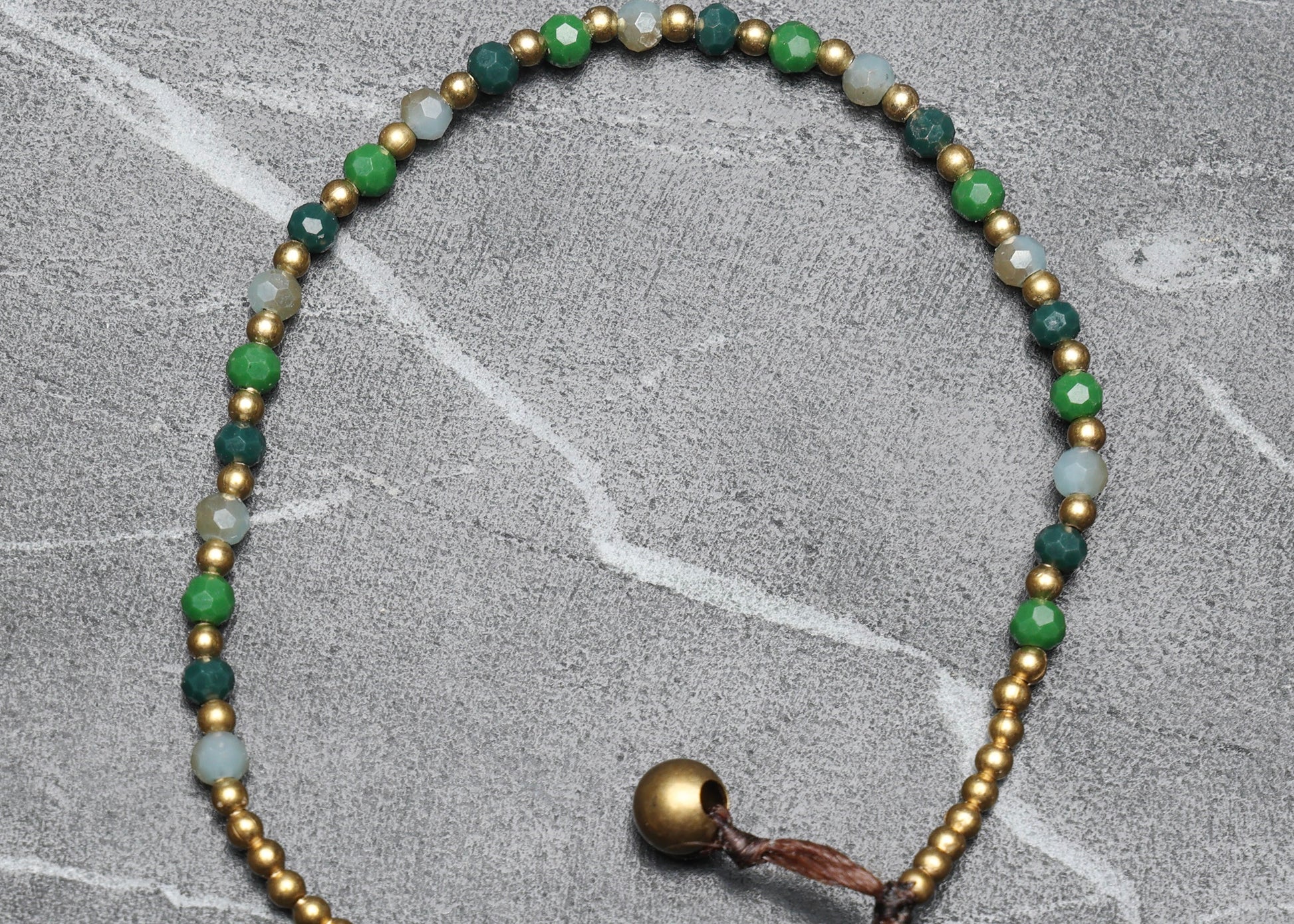 A crystal healing bracelet made of faceted Aventurine crystals on a cotton cord with brass beads