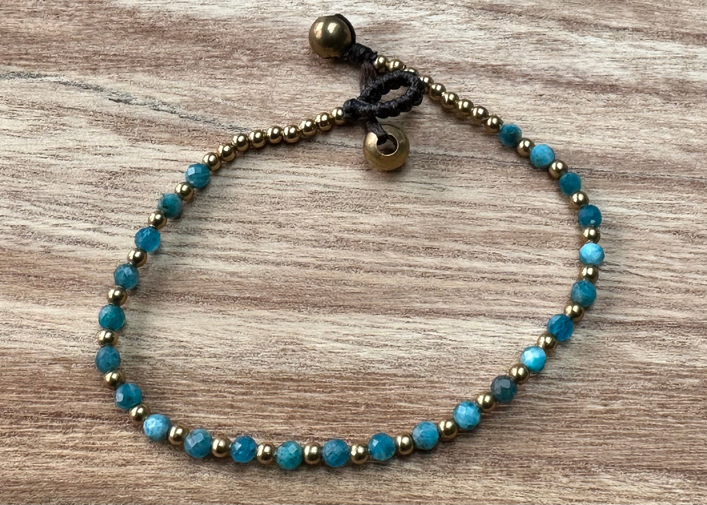 A crystal healing bracelet made of faceted Blue Apatite crystals on a cotton cord with brass beads.